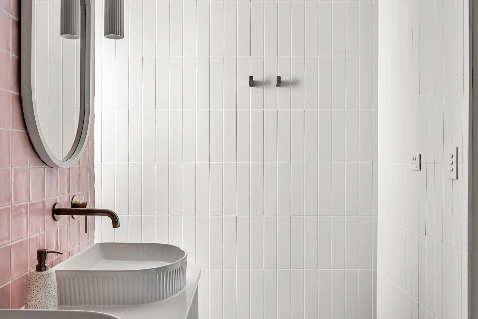 Contemporary bathroom featuring minimalist design with pink and white tiles and a sleek faucet