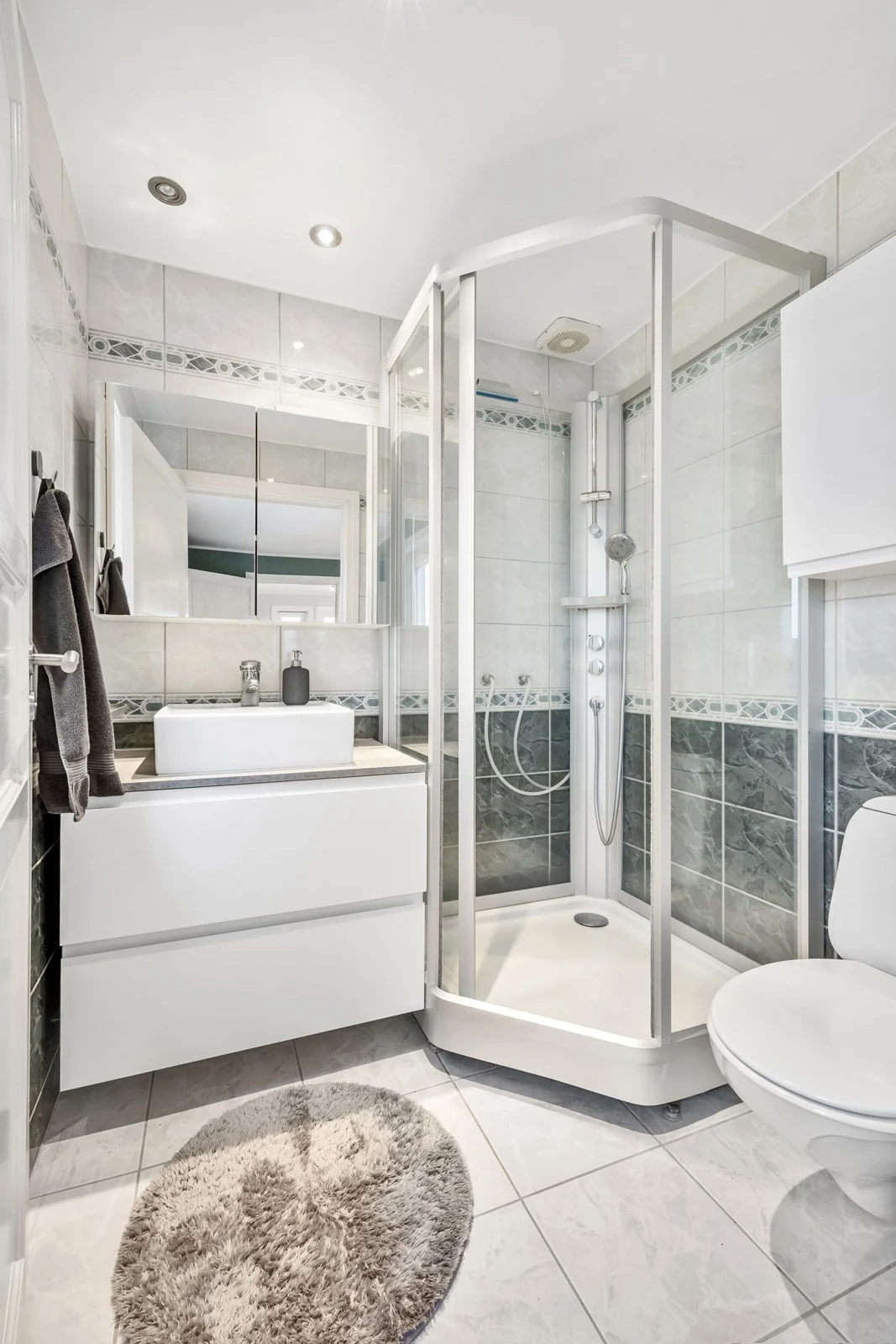 Elegant bathroom featuring a glass shower, modern white fixtures, and tile flooring, showcasing minimalistic and contemporary design