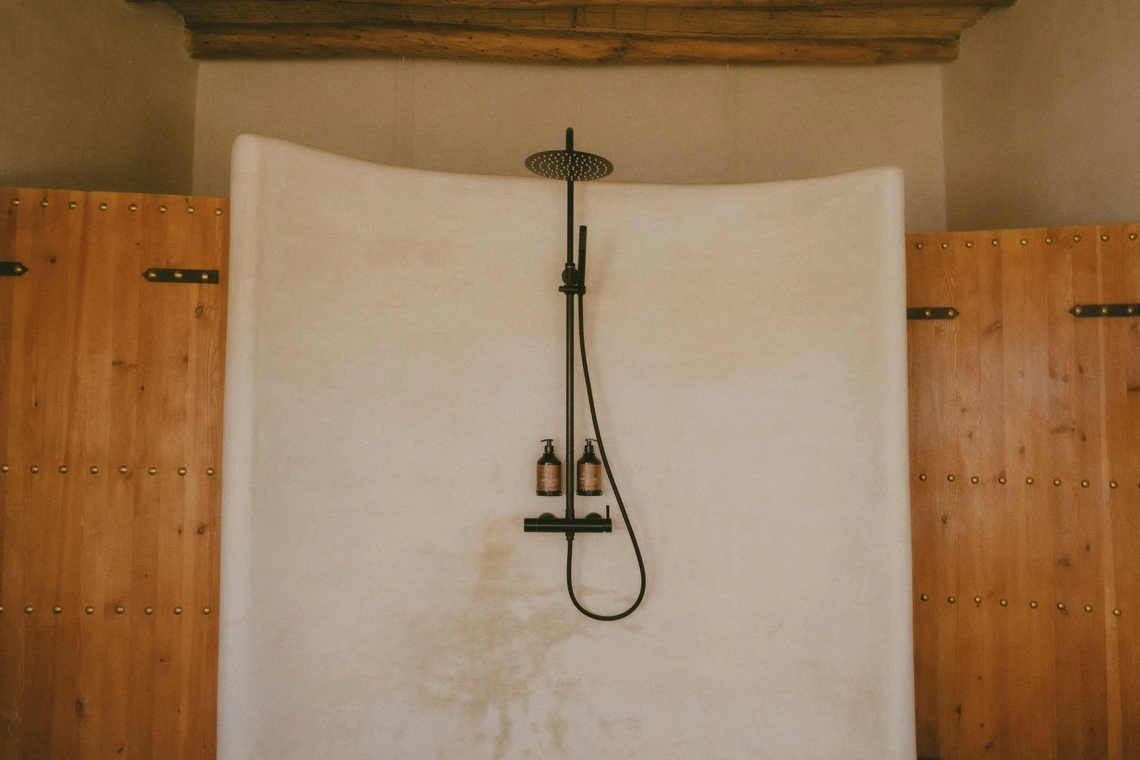 Elegant rustic shower setup in a traditional Moroccan bathroom with wooden doors