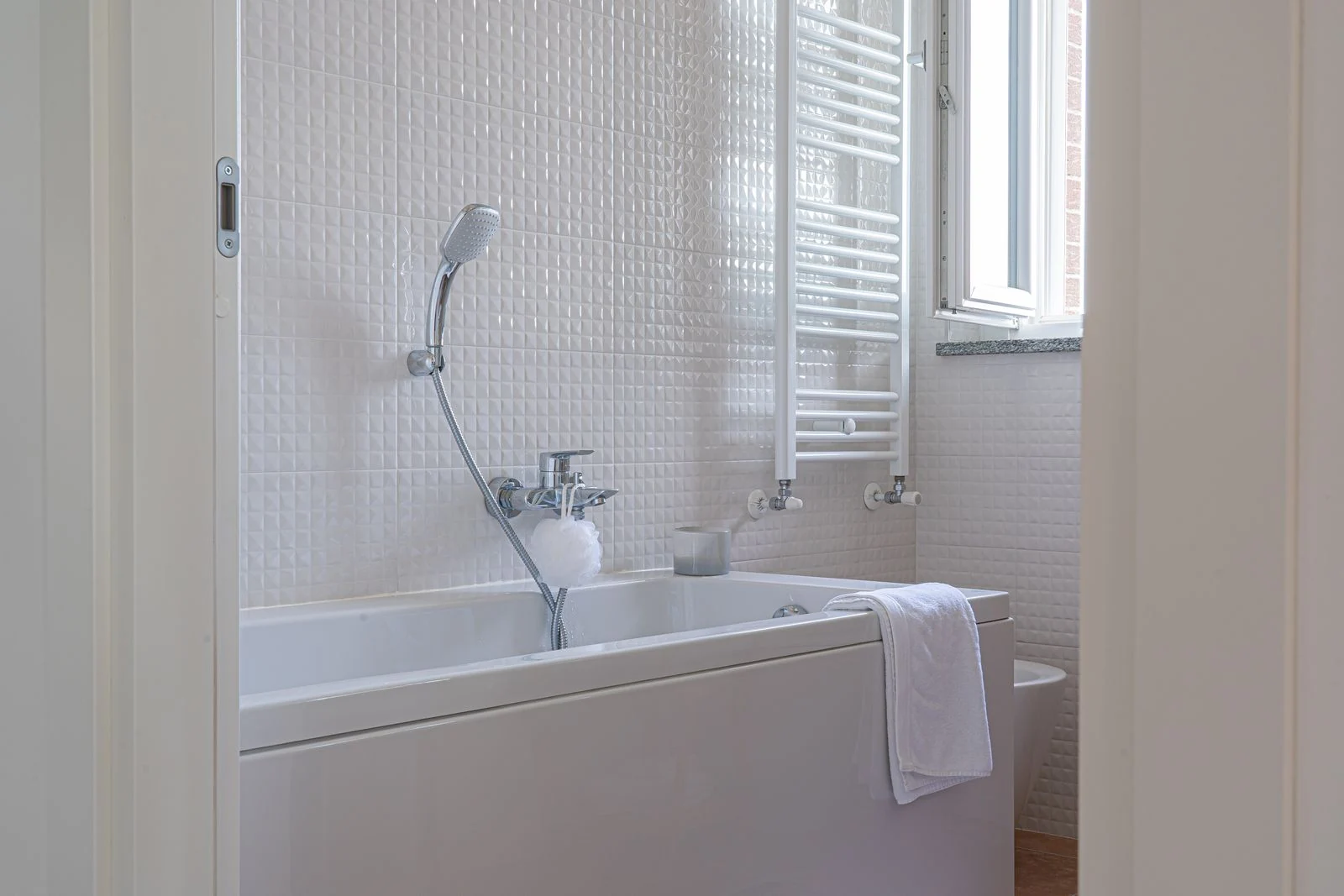 Bright and sleek bathroom featuring a bathtub, towel, and showerhead