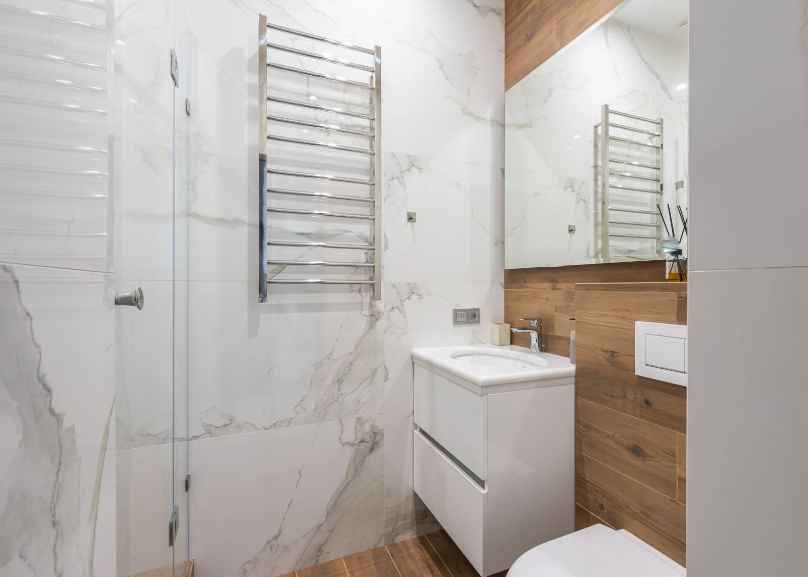 Interior of light bathroom with washbasin placed under mirror and white toilet in modern apartment