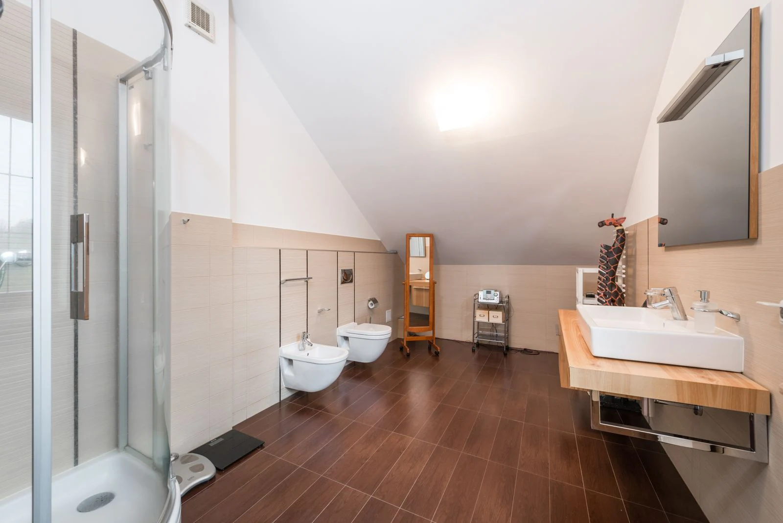 Minimalistic design interior of contemporary spacious bathroom with glass shower cabin next to bidet and toilet near sink with mirror in modern house