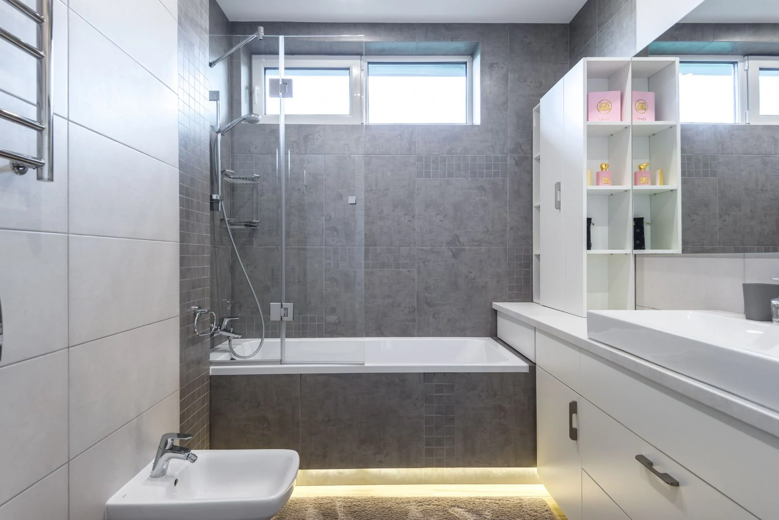 Contemporary bathroom featuring sleek gray tiles, bathtub, shower, and vanity