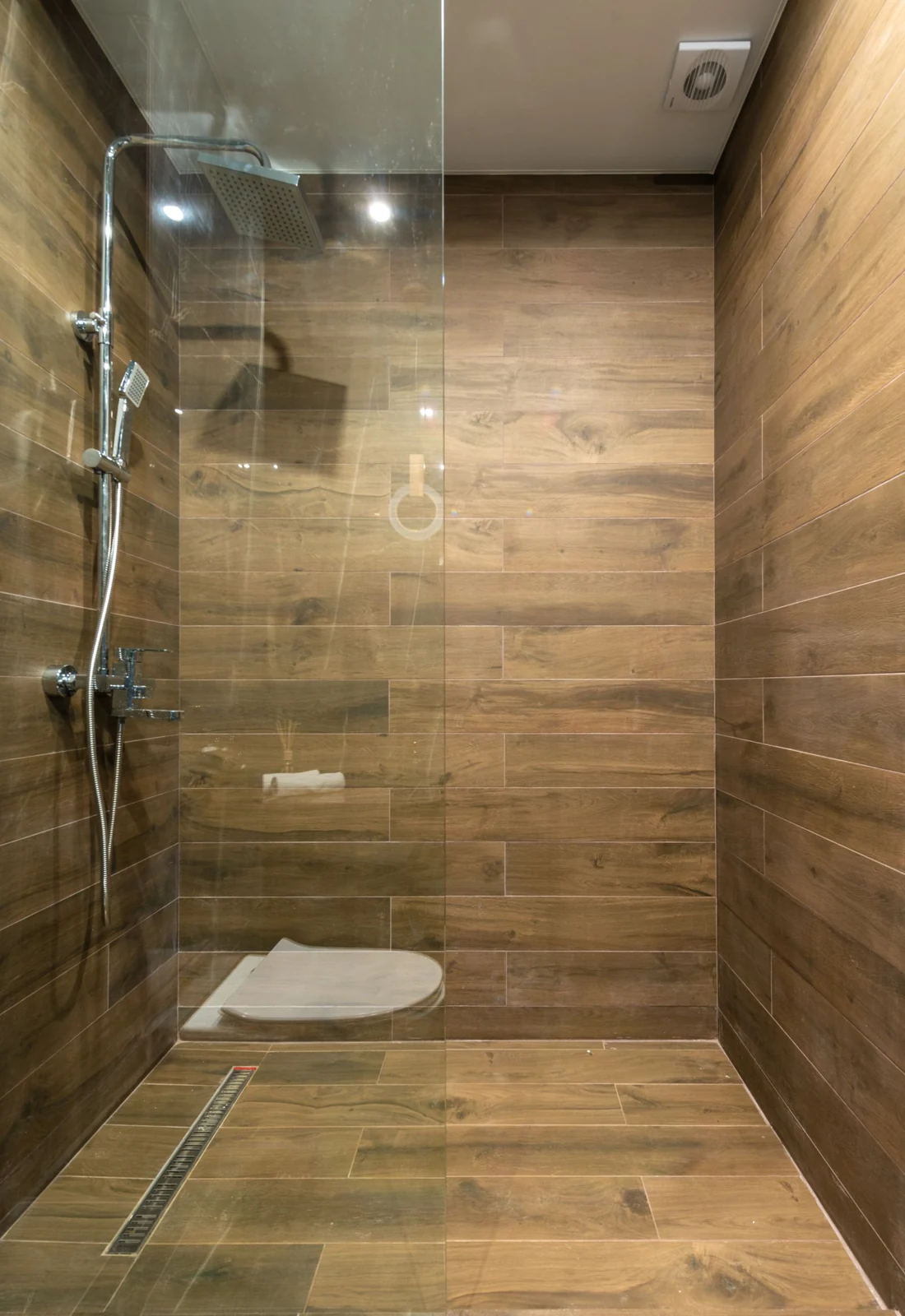 Elegant wooden-themed shower stall with clean glass partition in a modern bathroom setting
